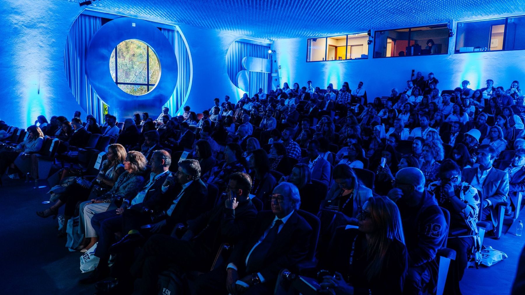 Plateia numa conferência NEXT.MARKETING, sala em luz azul